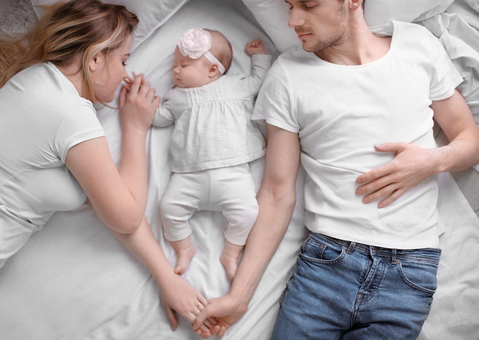 Young Parents Co-Sleeping with Baby Girl on Bed at Home